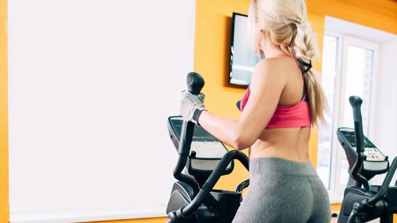 Fitness young girl on elliptical machine