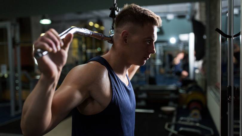 Man Flexing Muscles on Pulldown bar