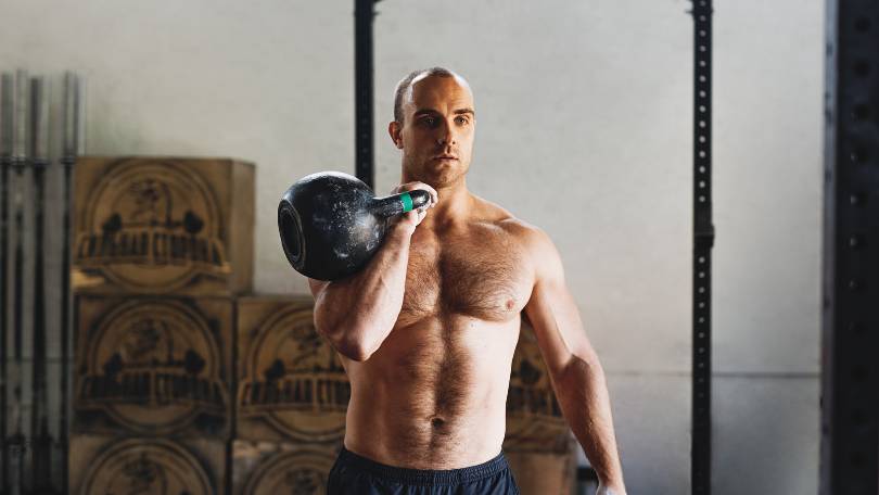 Man doing Russian kettlebell swings in gym